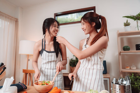 Young Women Asian Food Cooking Preparation Salad Vegetable Kitchen Lifestyle Healthy Eating, Joyful Moments of Healthy Meal Making and Togetherness in a Cozy Home Kitchen Full of Freshness and Smilesの写真素材