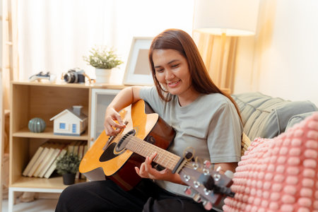 Woman Asian Playing Music Guitar Lifestyle Relax Lesson Fun Relaxation, Cheerful Moment of Home Guitar Practice, Sharing Joy and Music in a Cozy Living Room with Acousticの写真素材