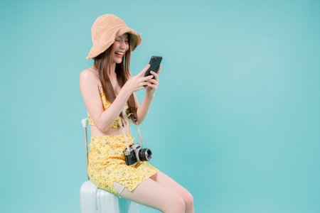 Asian Woman using smartphone for booking and buying ticket Online, Young Woman Holding a Mobile Phone Summer Vacation Concept on studio background.の写真素材