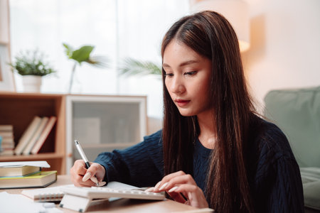 Student Studying and Doing Homework Woman Young University Female Reading Education Writing, Focused Young Adult Engaged in Learning and Academic Work at Home, Preparing for Successの写真素材