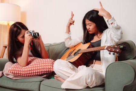Asian Woman Music Guitar Playing Togetherness Song Teenage Indoor Living Room, Joyful Gathering of Friends Sharing Music, Laughter, and Relaxation Through Guitar Playing at Homeの写真素材