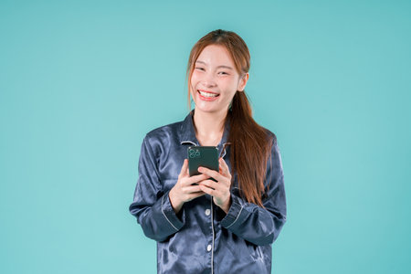 .Self Phone Sleep Woman Using Smart Phone Online Relaxation with Eye Cup and Pillow, A Young Woman Holding Smartphone in Bed, Smiling with Tired Eyes, Embracing a Peaceful Digital Morning.の写真素材
