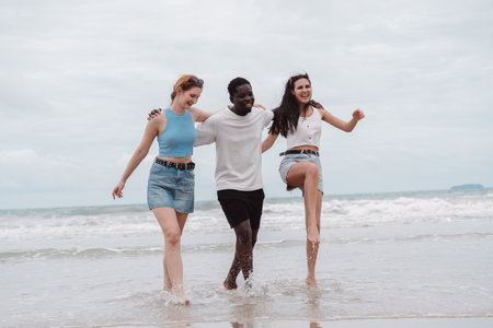 Diverse group of friends walking the beach, enjoying freedom and fun in summer vacation. happiness, and multicultural friendshipの写真素材