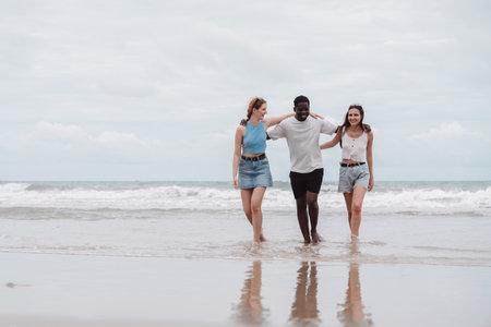 Diverse group of friends walking the beach, enjoying summer vacation together. Multicultural friendship and travel concept with happiness and connection.の写真素材