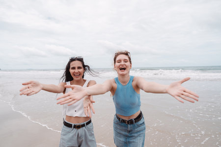 Two young women smiling on the beach, joyful friendship, summer vibes, travel fun, energy. lifestyle, holiday, and beach vacation concepts.の写真素材