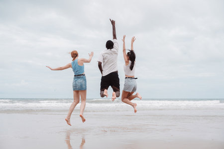 Diverse group of young friends enjoying a fun moment on the beach, laughing together. summer lifestyle, freedom, and multicultural friendship.の写真素材