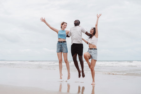 Happy diverse group of young people jumping on the beach, enjoying summer travel and friendship....