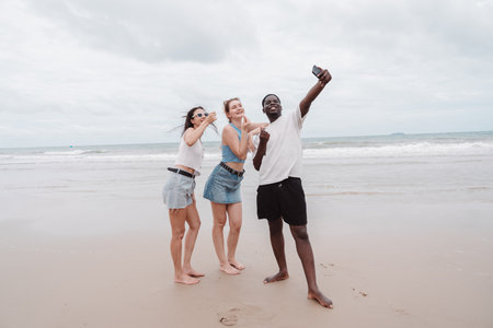 Diverse group of young friends taking selfie and enjoying time together on the beach. Fun summer...