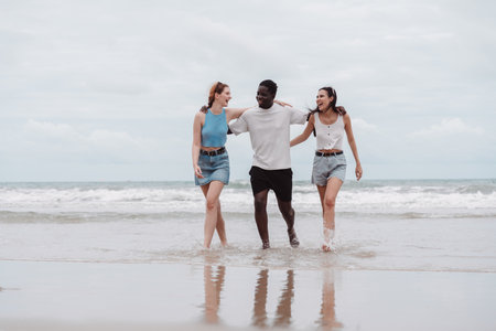 Diverse group of friends walking the beach, enjoying summer vacation together. Multicultural friendship and travel concept with happiness and connection.の写真素材