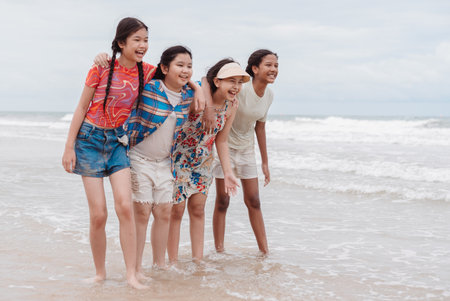 Happy group of diverse Asian and multicultural kids and daughters enjoying time together on the beach. Expressing joy, childhood freedom, and summer adventure by the sea.の写真素材