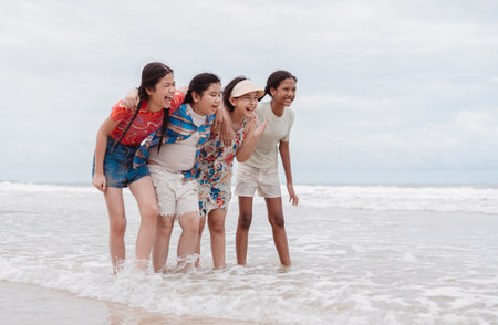 Happy group of Asian daughters and multicultural kids laughing and playing together on the beach. joy, friendship, freedom, and childhood happiness outdoors.の写真素材