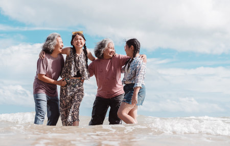 Happy Asian family across generations enjoying the beach. Seniors and children joyful smiles,...