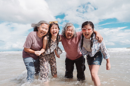 Asian family generations smiling together in the sea. Joyful moment of love, health, retirement wellness, and emotional in a carefree beach lifestyle.の写真素材