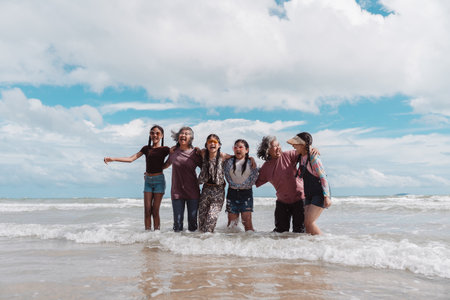 Relaxed Asian family with senior women and children enjoying time together at the beach. Celebrating wellness, love, and intergenerational connection in a joyful coastal moment.の写真素材