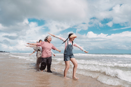 Happy Asian family enjoying beach time together. Seniors and children walking playfully, wellness,...