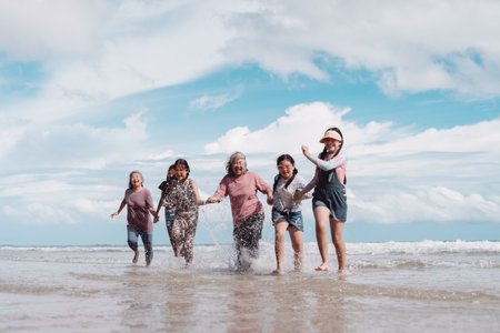 Happy Asian family running the beach, Seniors and kids. joyful family travel, healthy retirement lifestyle, freedom, and outdoor wellness.の写真素材