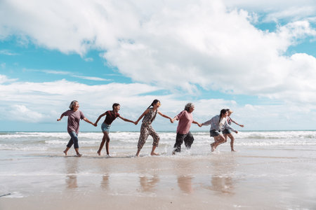 Asian family running happily the beach, healthy retirement lifestyle, strong family relationships, joyful aging, and the importance of planning with insurance and care.の写真素材