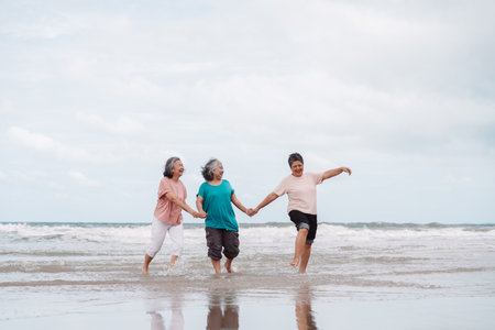 Asian senior females walking on the beach, smiling and enjoying retirement freedom. insurance, life plan, and healthy senior lifestyle.の写真素材