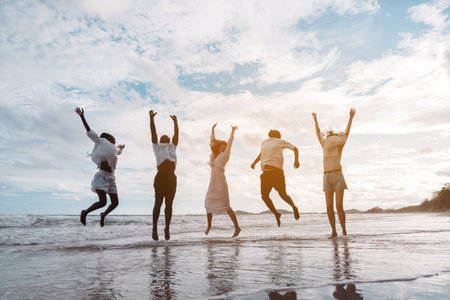 Happy diverse group of friends jumping on the beach, enjoying freedom, movement, and summer fun....