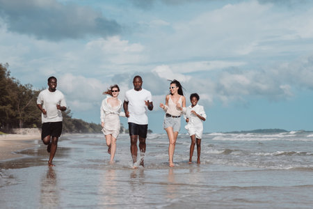Diverse group of friends running together on the beach. Active friendship, summer fun, freedom, and energetic lifestyle by the sea.の写真素材