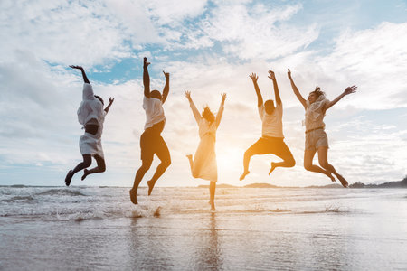 Diverse group of joyful friends jumping together on the beach with energy and excitement. freedom, active lifestyle, celebration.の写真素材