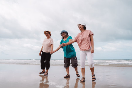Asian elderly women enjoying a carefree moment on the beach, laughing and walking together along the...
