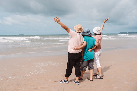 Senior women enjoying a vacation at the beach, standing together and looking at the sea. Concept of...
