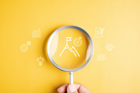 Mission target and goal achievement with magnifying glass on mountain peak and flag, vision, strategy, planning, business success, and accomplishment.の写真素材