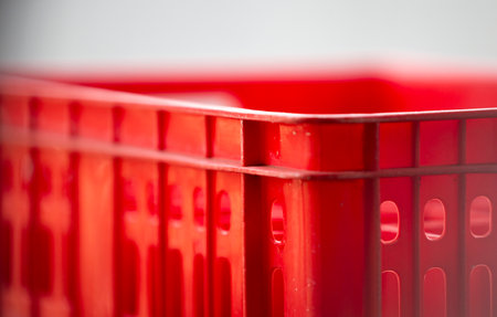 Red plastic shopping basket on white background, shallow depth of field.の写真素材