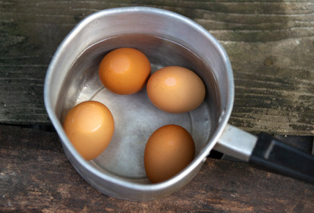 Boiled eggs in a metal pan on a wooden table. Top view.の写真素材