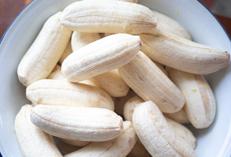 Peeled bananas in a bowl on wooden background. Close up.の写真素材
