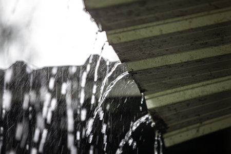 Rain drops on the roof of a house with a green background.の写真素材
