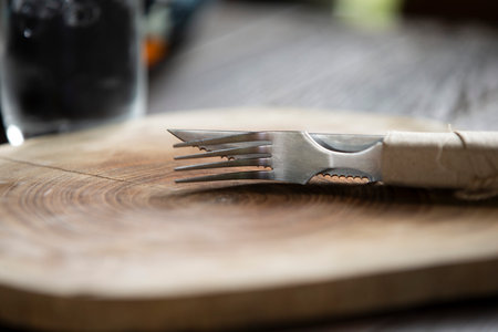 knife and fork on a wooden plate in a restaurant, selective focus