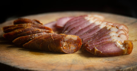 slices of smoked meat on a wooden board, close-upの写真素材
