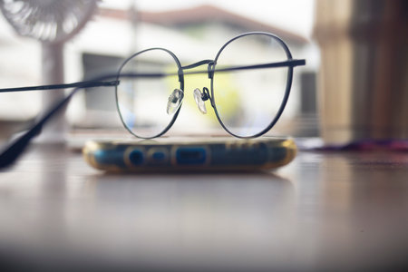 Eyeglasses and mobile phone on the table. Selective focus.