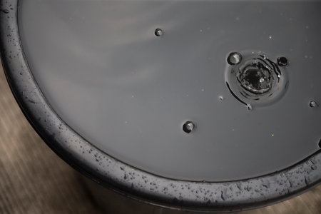 water drop falling from the top of a black bowl on a wooden background