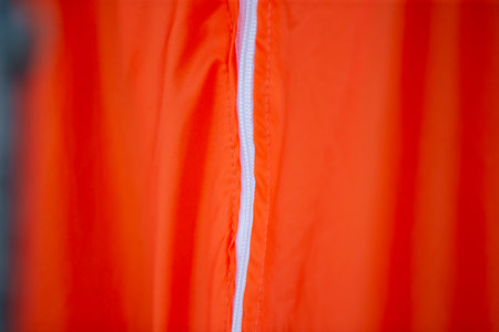 Close up of an orange raincoat with a white stripe on it
