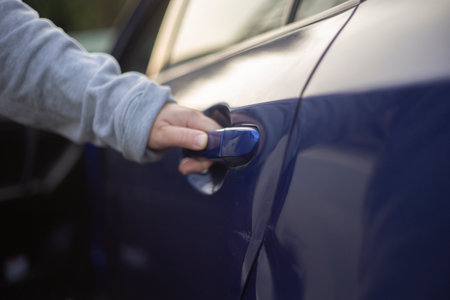 Close up of woman's hand opening blue car door with key.の写真素材