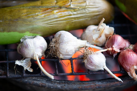 Garlic and cucumber on the grill with flames in the backgroundの写真素材