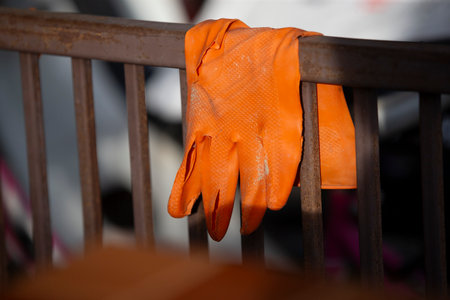 Orange protective gloves on the iron fence. Close-up. Selective focus.