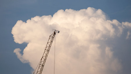 Crane on a background of blue sky with white clouds and sunの写真素材