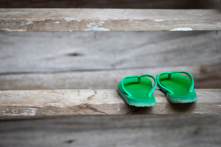 Green flip flops on wooden background.の写真素材