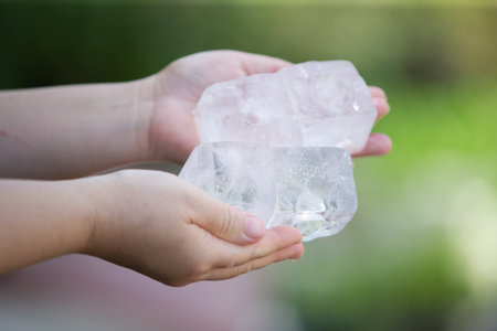 Ice cubes in the hands of a child. Selective focus.の写真素材
