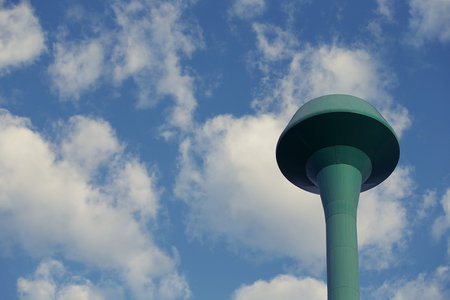 Water tower against blue sky with white clouds, closeup of photo
