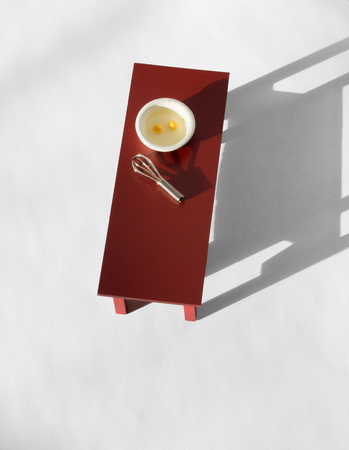 Two eggs in bowl with whisk on table, shot from above, white floorの写真素材