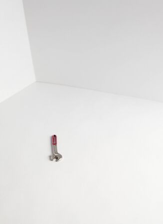 Wrench with red handle on floor in corner of white roomの写真素材