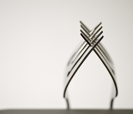 Tines of two forks intertwined/balanced with isolated white background.の写真素材