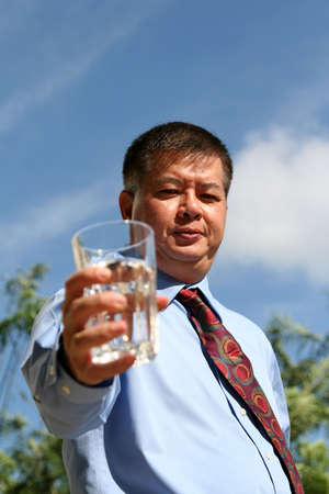 Asian man holding a glass of water over the blue sky の写真素材