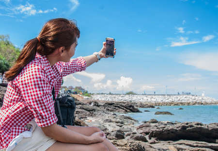Women playing smartphone on the rocks.の写真素材