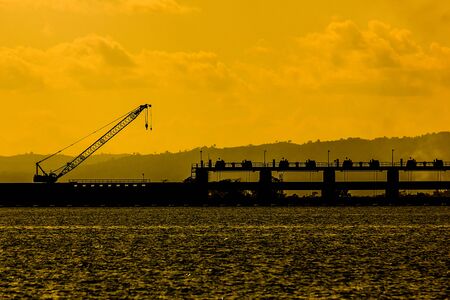 Silhouette of the dam at colorful sunset and over color. With parking Heavy machineryの写真素材